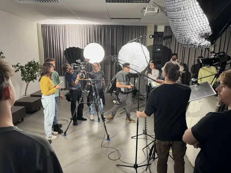 A Movie Sprint crew at work on set: performers, a camera operator on sticks, a boom operator and lights on stands