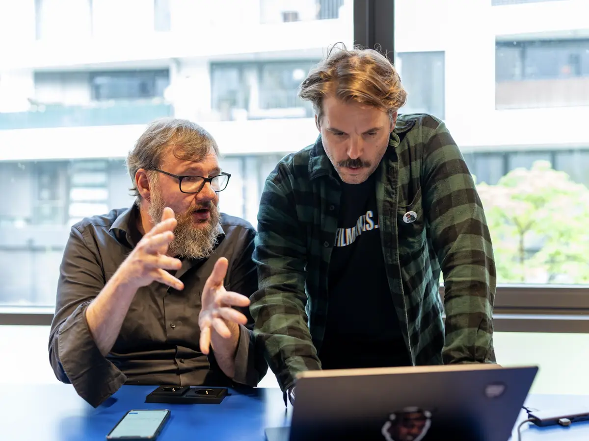 Two filmmakers work something out together at a laptop